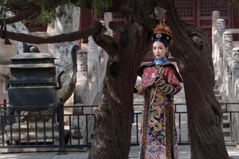 穿清宫服的青年女人站在古树下东亚写实摄影图