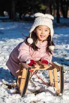 快乐的小女孩在雪地上玩雪橇