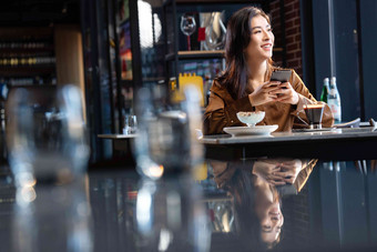 咖啡馆内边喝咖啡边使用<strong>手机</strong>的青年女人饮料氛围摄影图