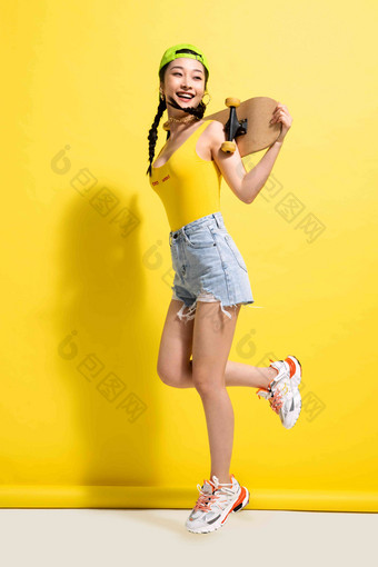 快乐的青年女人背着滑板跳写实照片