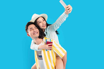 青年男人背着女朋友用手机自拍年轻人氛围照片