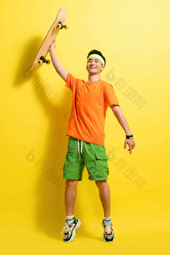 快乐的青年男人举着滑板锻炼高清图片