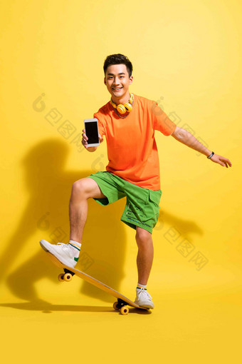拿着手机玩滑板的青年男人快乐氛围场景
