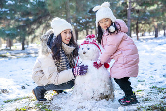 快乐的母女推雪人相伴高端图片