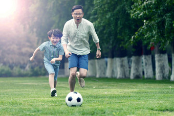 快乐<strong>父子</strong>在草地上踢足球白昼清晰影相