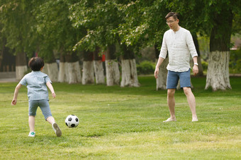 快乐父子在草地上踢足球温馨摄影