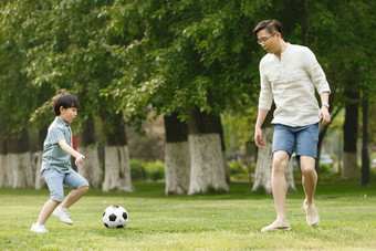 快乐父子在草地上踢足球公园清晰相片