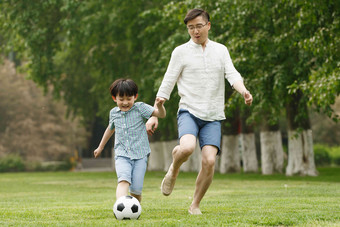 快乐父子在草地上踢足球高兴照片