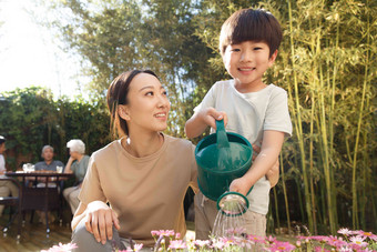 母亲和儿子在花园里浇花花盆高端影相