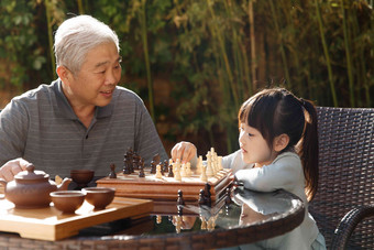 祖父和孙女在庭院里下棋
