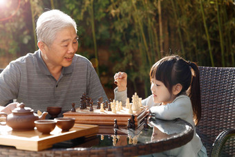 祖父和孙女在庭院里下棋