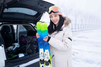 青年女人从后备箱拿滑雪板