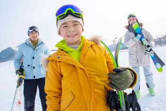 雪场上拿着滑雪板的一家三口冬天高质量摄影