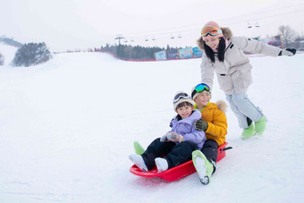 滑雪场上妈妈推着坐在雪上滑板的孩子们儿童高清拍摄