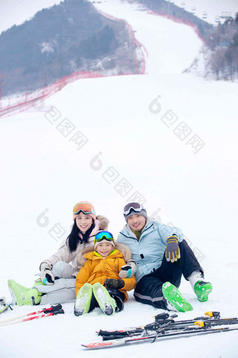 雪场上坐在雪道上的一家三口