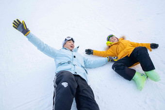 快乐的父子在雪地上躺着玩耍滑雪运动亚洲高质量摄影