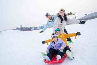 滑雪场上父母和坐在雪上滑板的孩子们户外氛围影相