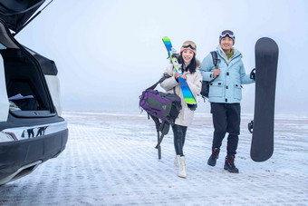 停车场上青年伴侣拿着滑雪板