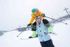 滑雪场上拿滑雪杖的快乐男孩骑在父亲脖子上