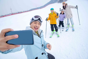 滑雪场上用手机自拍的一家四口