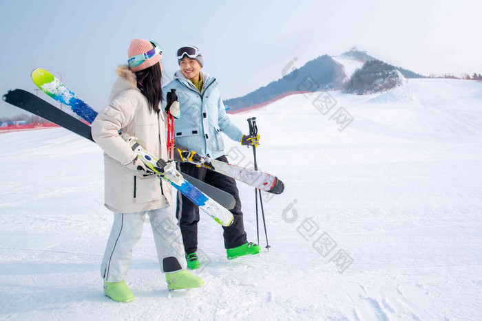 青年伴侣拿着雪具在滑雪场行走青年女人高端影相