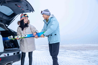 青年夫妻往汽车后备箱里装滑雪板站着高质量场景