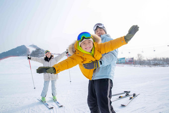 滑雪场上抱着儿子飞的父亲和滑雪的母亲