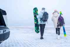 青年伴侣拿着滑雪板的背影
