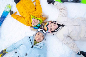 快乐的一家三口躺在雪地上关爱高端摄影