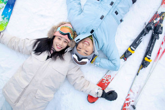 快乐的青年伴侣躺在雪地上露齿一笑高清场景