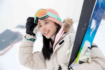 滑雪场上抱着滑雪板漂亮的青年女人