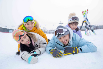 幸福的一家四口趴在雪地上母亲摄影图