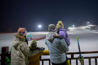 滑雪场看夜景的一家四口的背影儿子写实摄影图