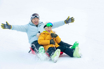 快乐父子坐着雪上滑板滑雪活力高端相片