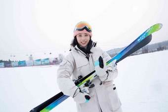 滑雪场上抱着滑雪板的青年女人防护镜素材