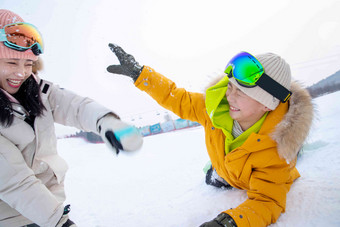 滑雪场内趴在地上打雪仗的快乐母子郊区高质量摄影