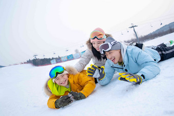 快乐的一家三口趴在雪地上玩耍丈夫写实素材