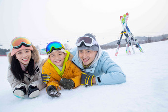 幸福的一家三口趴在雪地上