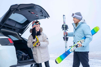 青年夫妻往汽车后备箱里装滑雪板享乐高清相片