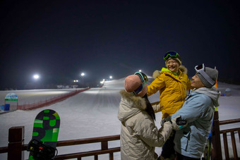 夜景下的滑雪场内的一家三口夜晚场景