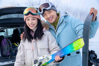 快乐的青年伴侣拿着滑雪板站z在一起