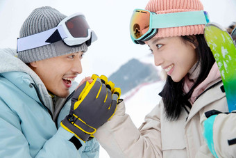 滑雪场上青年男人给女朋友捂手