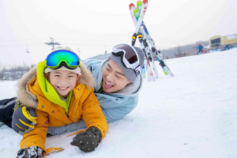 滑雪场内抱在一起打滚的快乐父子抱着写实影相