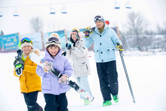 雪场上拿着雪具去<strong>滑雪</strong>的一家四口