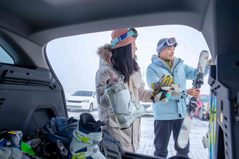 停车场内青年伴侣从汽车后备箱拿雪具冬天清晰拍摄