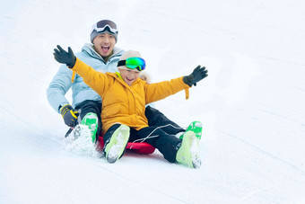 快乐父子坐着雪上滑板滑雪