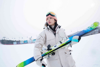 滑<strong>雪</strong>场上抱着滑<strong>雪</strong>板看远方的青年女人站着高端图片