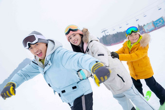 滑雪场上踩着滑雪板排队行走的一家三口人图片