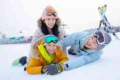 幸福快乐的一家三口趴在雪地上玩耍