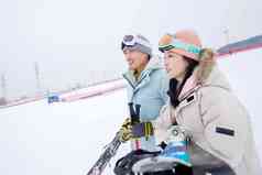 雪场上拿着滑雪板滑雪杖的快乐情侣
